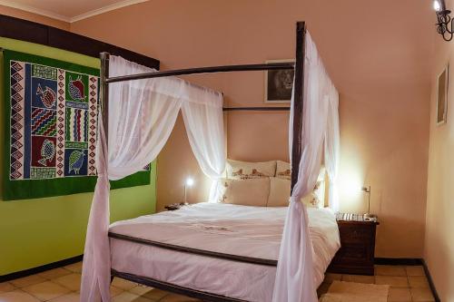 a bedroom with a canopy bed with white curtains at Chameleon Backpackers & Guesthouse in Windhoek