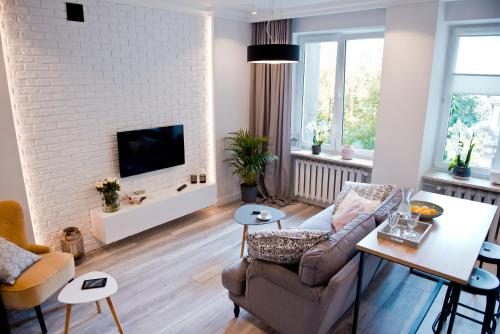 a living room with a couch and a tv on a white brick wall at Apartment next to the Old Town & Krasinski garden in Warsaw