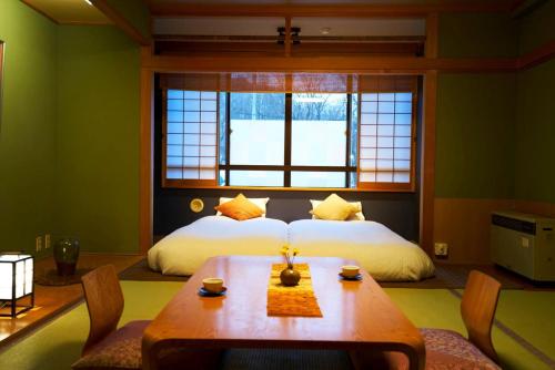 a bedroom with a bed and a table with chairs at Meitoya So in Zao Onsen