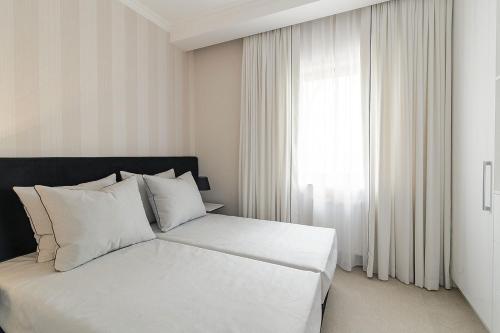 ソポトにあるPremier Apartment with Sauna by Grand Apartmentsの白い枕と窓が備わる白いベッド
