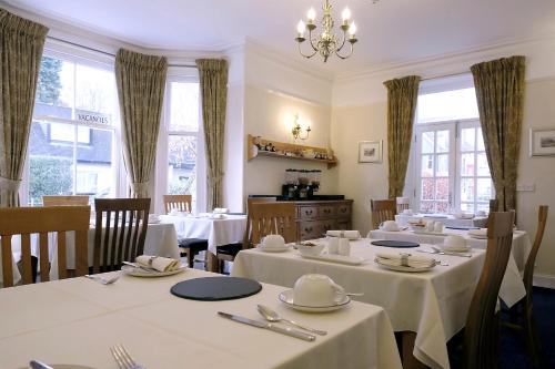 a restaurant with white tables and chairs and windows at Sunnyside Guest House in Keswick