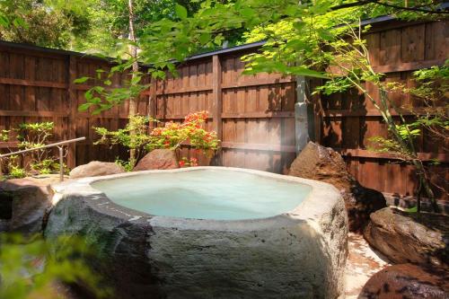 a large stone tub in a yard with a fence at Meitoya So in Zao Onsen