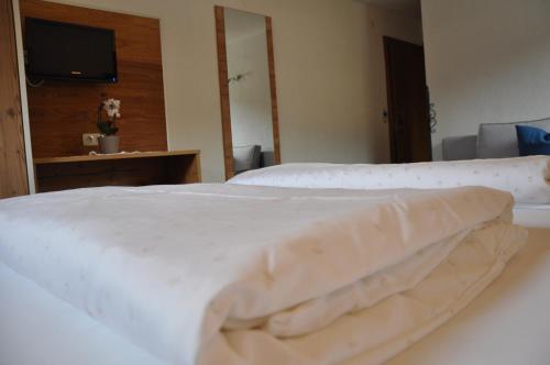 a bedroom with a white bed and a television at Berghof in Berwang