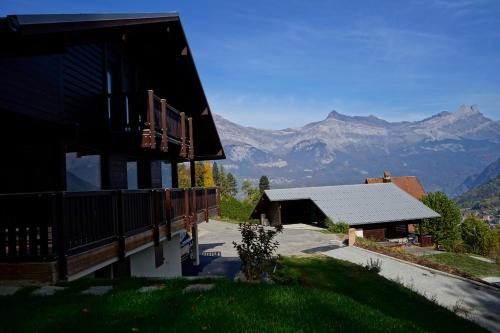 a house with a balcony and mountains in the background at Chalet Kizuna in Saint-Gervais-les-Bains