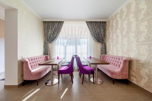 a dining room with two tables and purple chairs at D Hotel in Krasnodar
