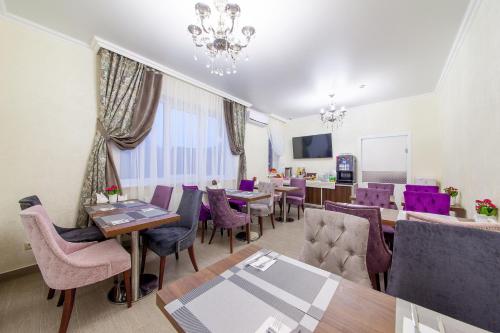 a dining room with tables and purple chairs at D Hotel in Krasnodar