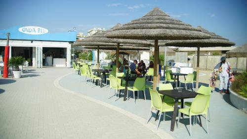 a group of tables and chairs with umbrellas on a patio at Appartamento Guido Reni in Lido di Spina