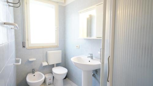 a white bathroom with a toilet and a sink at Appartamento Guido Reni in Lido di Spina