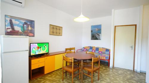 a dining room with a table and a refrigerator at Appartamento Guido Reni in Lido di Spina
