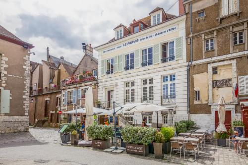 une rue avec des bâtiments, des tables et des parasols dans l'établissement Le Parvis, à Chartres