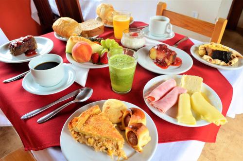 Una mesa cubierta con platos de desayuno y bebidas. en Pousada Flores da Serra, en Monte Verde
