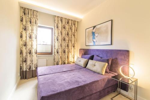 a bedroom with a purple bed and a window at Executive Apartment with Sauna by Grand Apartments in Sopot