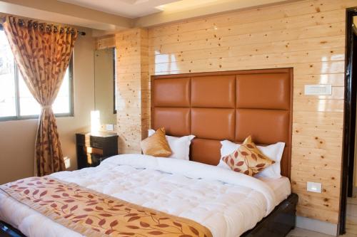 a bedroom with a large bed with a wooden wall at Valley View Residency in Darjeeling