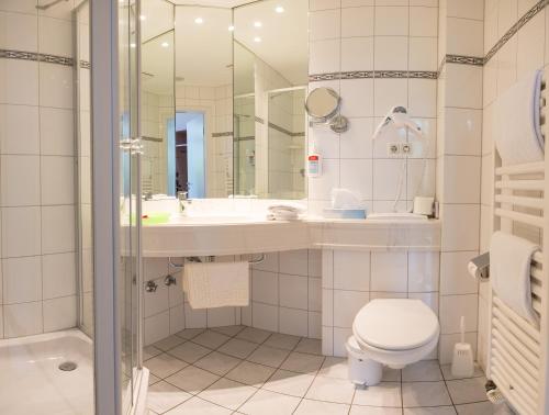 ein Bad mit einem Waschbecken, einem WC und einer Dusche in der Unterkunft BE BIO Hotel be active in Tönning