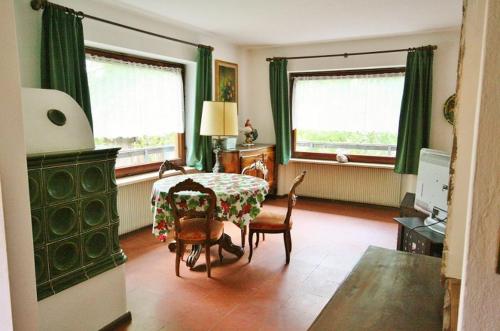 a living room with a table and chairs and two windows at Casa Iolanda in Soraga