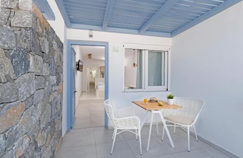 comedor con pared de piedra, mesa y sillas en Anatoli Luxury Studios & Suites, en Astipalea
