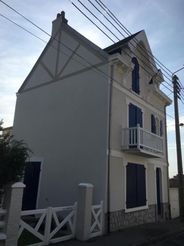 Cette maison blanche dispose d'une terrasse couverte et d'un balcon. dans l'établissement Villa Les Abeilles - Wimereusienne, à Wimereux