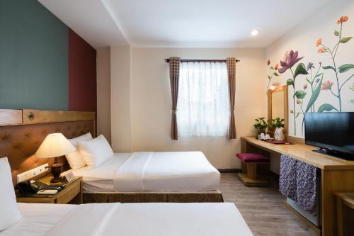 a hotel room with two beds and a television at Asian Ruby Hotel & Spa - 122F Bui Thi Xuân Street in Ho Chi Minh City