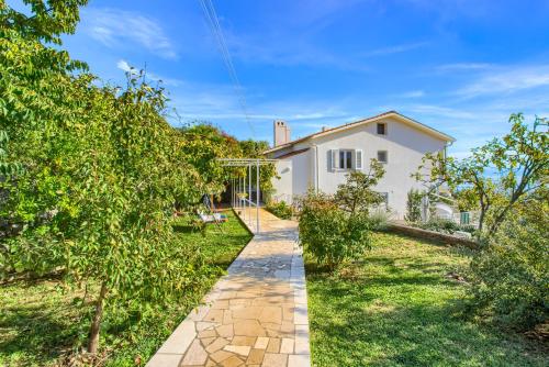 a garden with a pathway leading to a white house at Apartments Frlan in Kastav