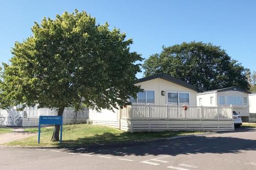 uma casa branca com uma árvore em frente em Mikanda Lodge em Clacton-on-Sea