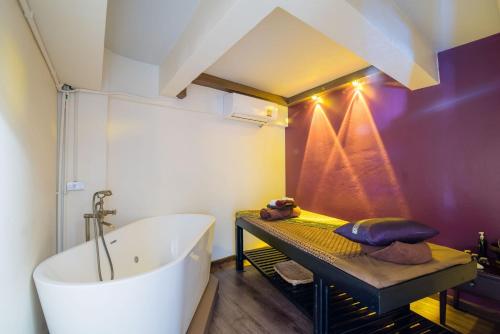 a bathroom with a white tub and a purple wall at Anchan Hotel & Spa in Hua Hin