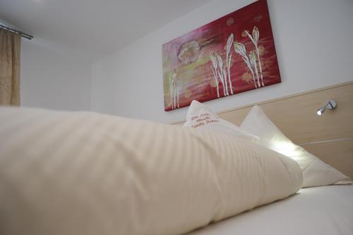 a bed with a white pillow and a painting on the wall at Hotel-Restaurant Steuermann in Karlsruhe