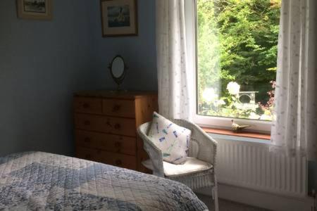 a bedroom with a bed and a dresser and a window at Millbrook in Helston