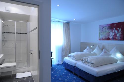 ein Schlafzimmer mit einem Bett und ein Badezimmer mit einer Dusche in der Unterkunft Hotel-Restaurant Steuermann in Karlsruhe