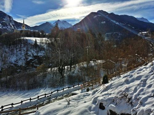 a snow covered hill with a fence and a church at Le Renard d'Introd in Introd