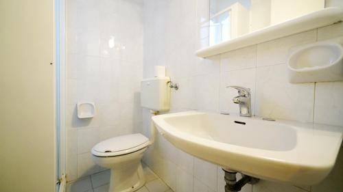 a white bathroom with a toilet and a sink at Villetta 6 in Lido degli Estensi