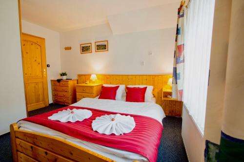 a bedroom with a large bed with red and white pillows at Chalet Schäfer s vyhřívaným bazénem se slanou vodou in Harrachov