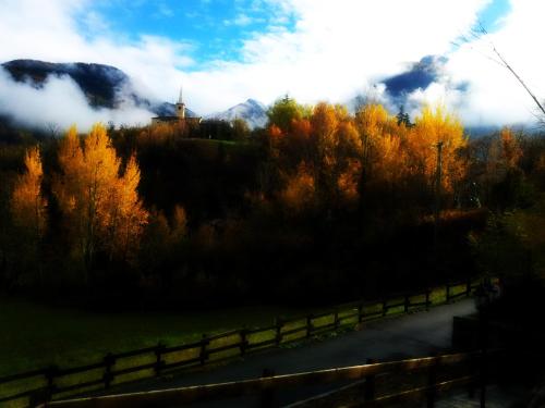 a road with a fence and trees and a mountain at Le Renard d'Introd in Introd