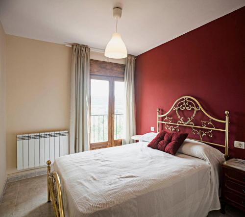 ヌエバロスにあるCasa rural la Era del Malañoの赤い壁のベッドルーム1室(大型ベッド1台付)