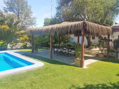 a large straw umbrella next to a swimming pool at Casa Calfu in Santa Cruz