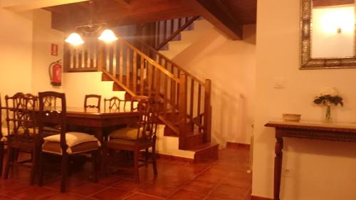 a dining room with a table and a wooden staircase at LAS PIÑONERAS in Tórtoles