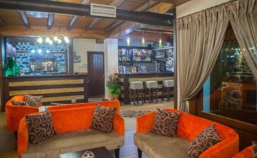 a living room with orange couches and a bar at Enastron in Palaios Agios Athanasios