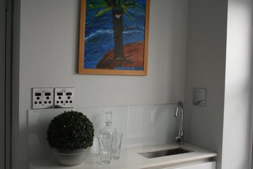 uma cozinha com um lavatório e uma pintura na parede em Wild Artz em Cidade do Cabo