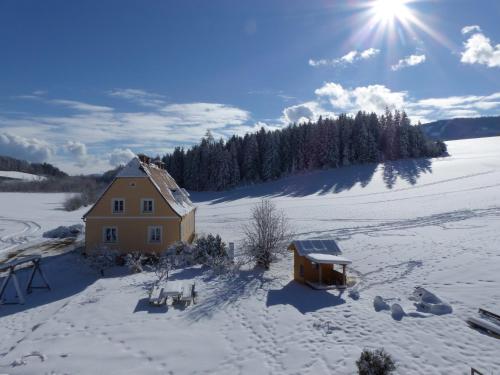 a house in a snow covered field with the sun at Ferienhaus Wohleser in Mariahof