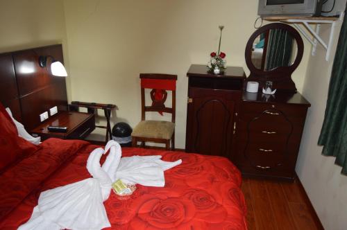 a bedroom with a red bed with towels on it at Balcones del Río Hotel in Latacunga