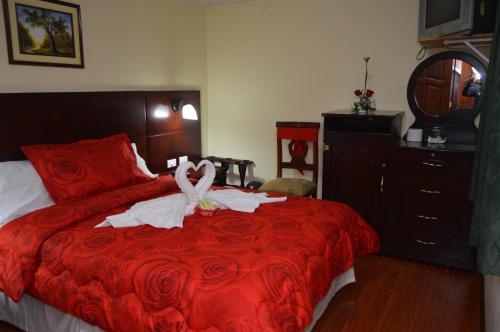 a bedroom with a red bed with a wedding dress on it at Balcones del Río Hotel in Latacunga