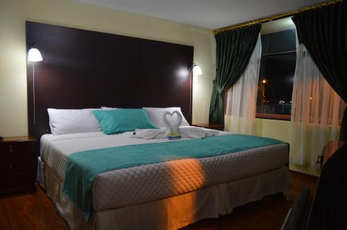 Un dormitorio con una cama grande y una ventana en Balcones del Río Hotel, en Latacunga
