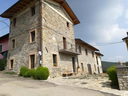 - un grand bâtiment en pierre avec un balcon sur le côté dans l'établissement Agricola Tre Rii Sidreria, à Corniglio