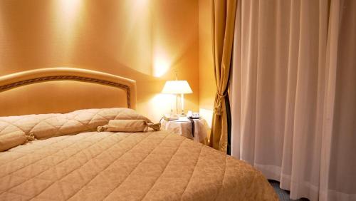 a bedroom with a bed and a lamp and curtains at 501 Hotel in Vibo Valentia