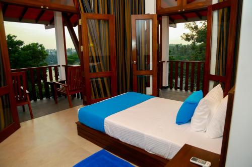 a bedroom with a bed and a balcony with windows at Seafood Restaurant and Motel in Tangalle