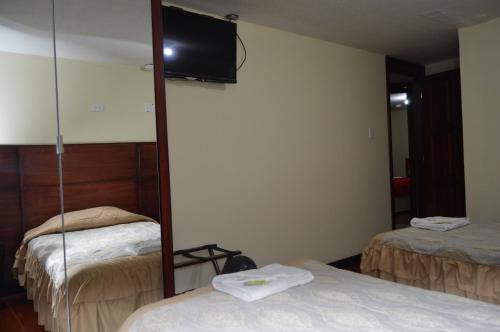 a hotel room with two beds and a mirror at Balcones del Río Hotel in Latacunga