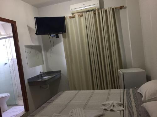a bedroom with a bed and a shower curtain at Hotel Huesca in Presidente Prudente