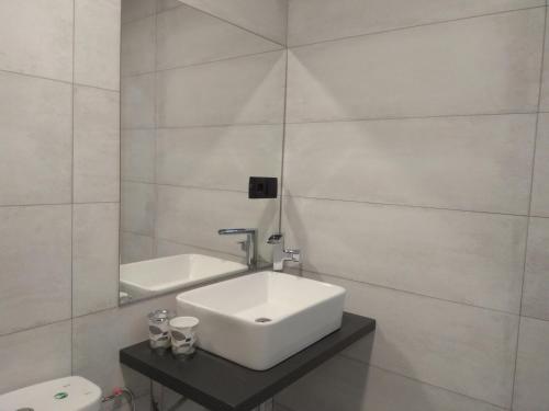 La salle de bains blanche est pourvue d'un lavabo et d'un miroir. dans l'établissement Caleros 8 Apartamento - Apartamentos de la Parte Antigua de Cáceres, à Cáceres