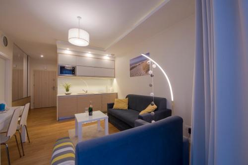 a living room with a blue couch and a table at Apartament DeLux Marina in Kąty Rybackie