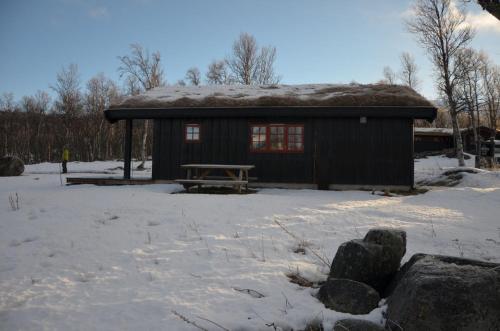 a small cabin with a picnic table in the snow at Northern gate Besseggen - Cottage no 17 in Besseggen Fjellpark Maurvangen in Maurvangen