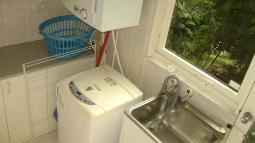 uma máquina de lavar roupa e um lavatório numa pequena cozinha em Accommodation Sydney North - Forestville 4 bedroom 2 bathroom house em Forestville